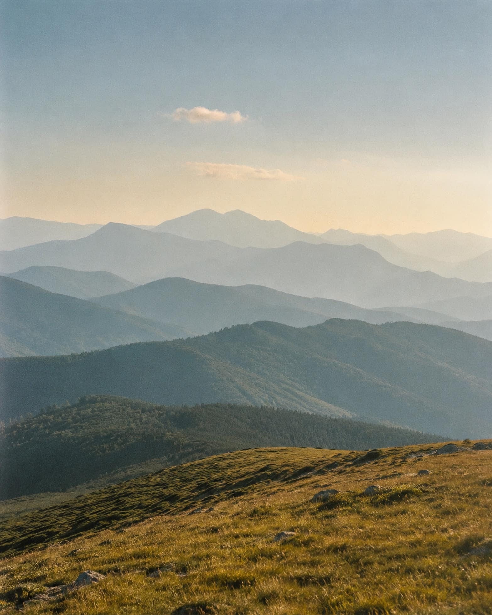 Layered mountain ridges fading into a hazy golden-hour sky